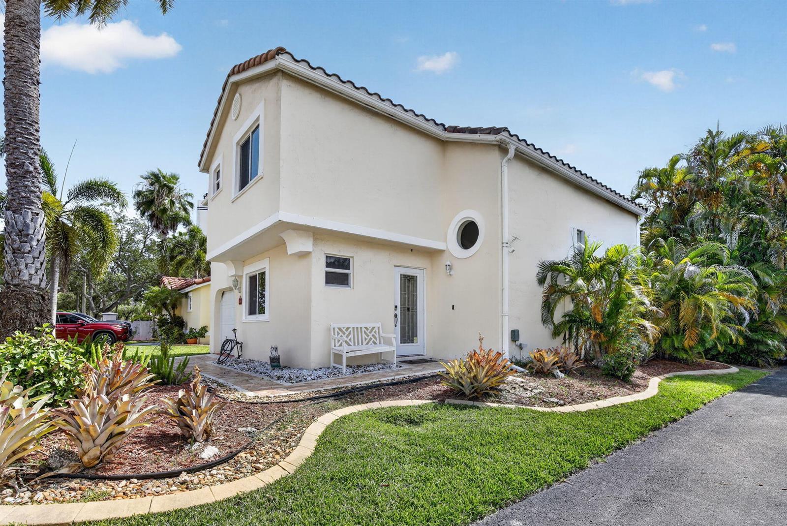 A two-story, light-colored stucco house with a tiled roof, circular window, and landscaped yard — 1306 SE 5th Court, Dania Beach FL 33004, DANIA BEACH, FL