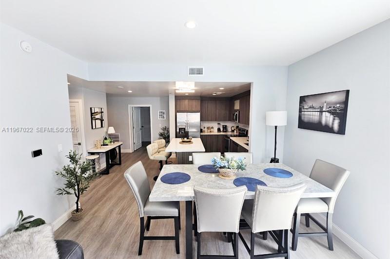 A dining area with a marble-topped table and chairs opens into a modern kitchen — 1938 Jackson St # 202, Hollywood FL 33020, HOLLYWOOD, FL