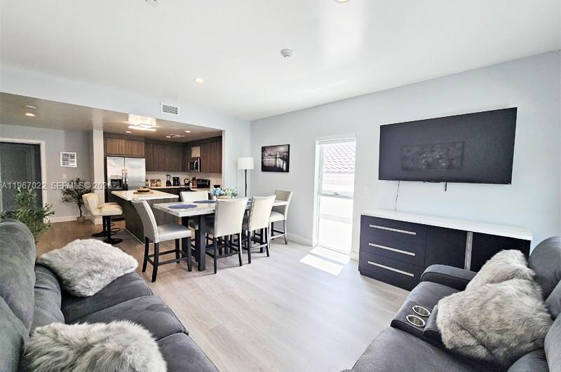 An open-concept living and dining area features a kitchen, dining table, and wall-mounted television — 1938 Jackson St # 202, Hollywood FL 33020, HOLLYWOOD, FL