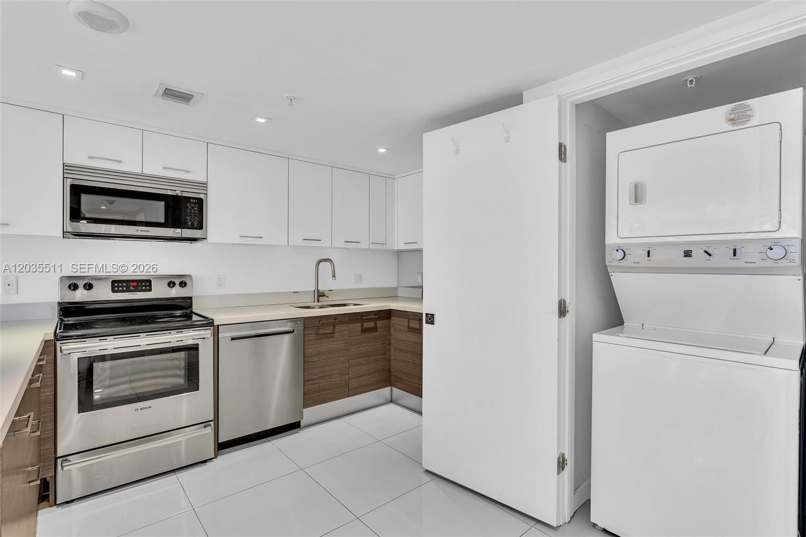 A kitchen features white upper cabinets, wood-tone lower cabinets, stainless steel appliances, and a laundry closet — 9901 E Bay Harbor Dr # 802, Bay Harbor Islands FL 33154, BAY HARBOR ISLANDS, FL