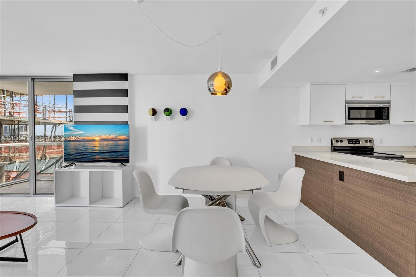 A modern dining area features a white table, four chairs, and a view of construction — 9901 E Bay Harbor Dr # 802, Bay Harbor Islands FL 33154, BAY HARBOR ISLANDS, FL
