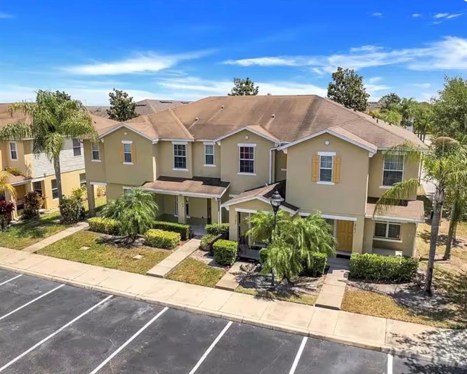 An exterior view of a two-story tan townhouse building with a brown shingled roof — 3109 SEAVIEW CASTLE DRIVE, KISSIMMEE, FL