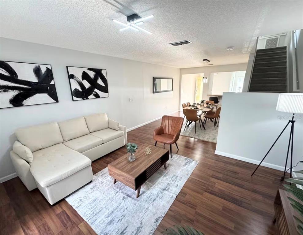 A living room with a sectional sofa, coffee table, and dining area with stairs nearby — 3109 SEAVIEW CASTLE DRIVE, KISSIMMEE, FL