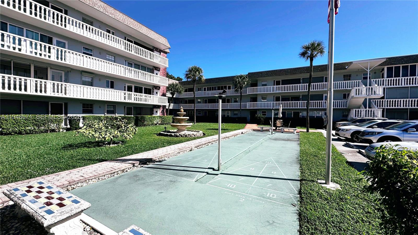 An outdoor shuffleboard court sits in the courtyard of a multi-story apartment complex — 1965 SE 5th Ct # 203, Pompano Beach FL 33060, POMPANO BEACH, FL