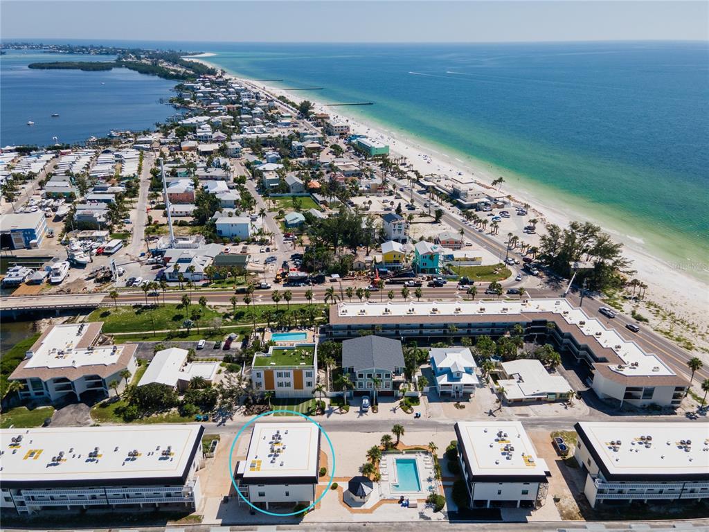 An aerial view shows a coastal resort area with a circled multi-story building and pool — 601 GULF DRIVE N UNIT 109, BRADENTON BEACH, FL