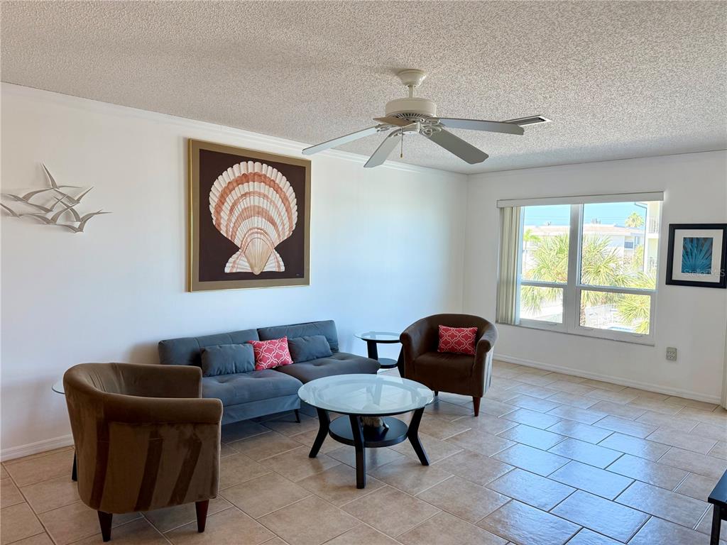 A living room features a gray sofa, two brown armchairs, a glass coffee table, and tile flooring — 601 GULF DRIVE N UNIT 109, BRADENTON BEACH, FL
