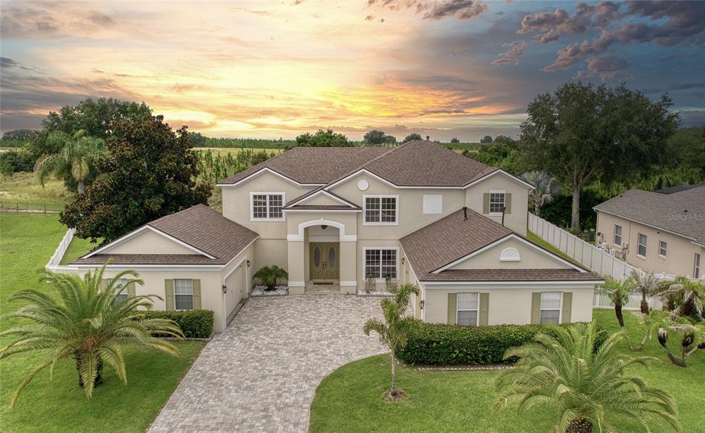 An aerial view of a two-story beige house with a paved driveway and palm trees — 2924 MAJESTIC ISLE DRIVE, CLERMONT, FL