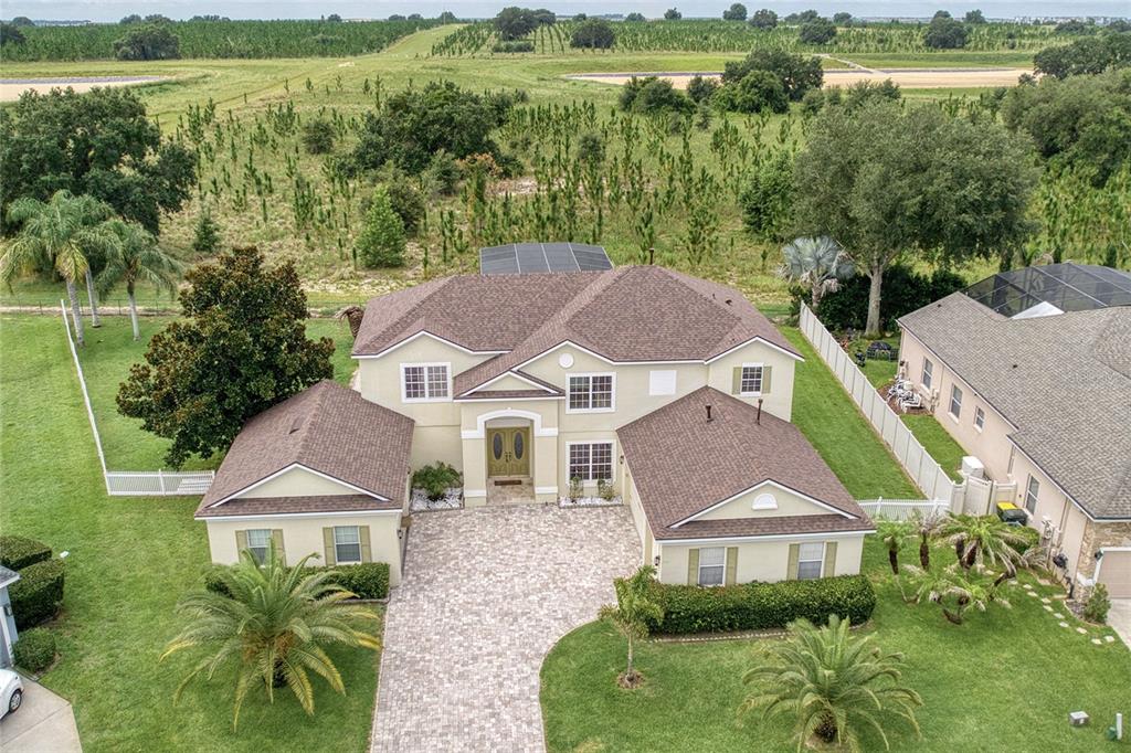 An aerial view shows a two-story house with a paver driveway and a large backyard — 2924 MAJESTIC ISLE DRIVE, CLERMONT, FL