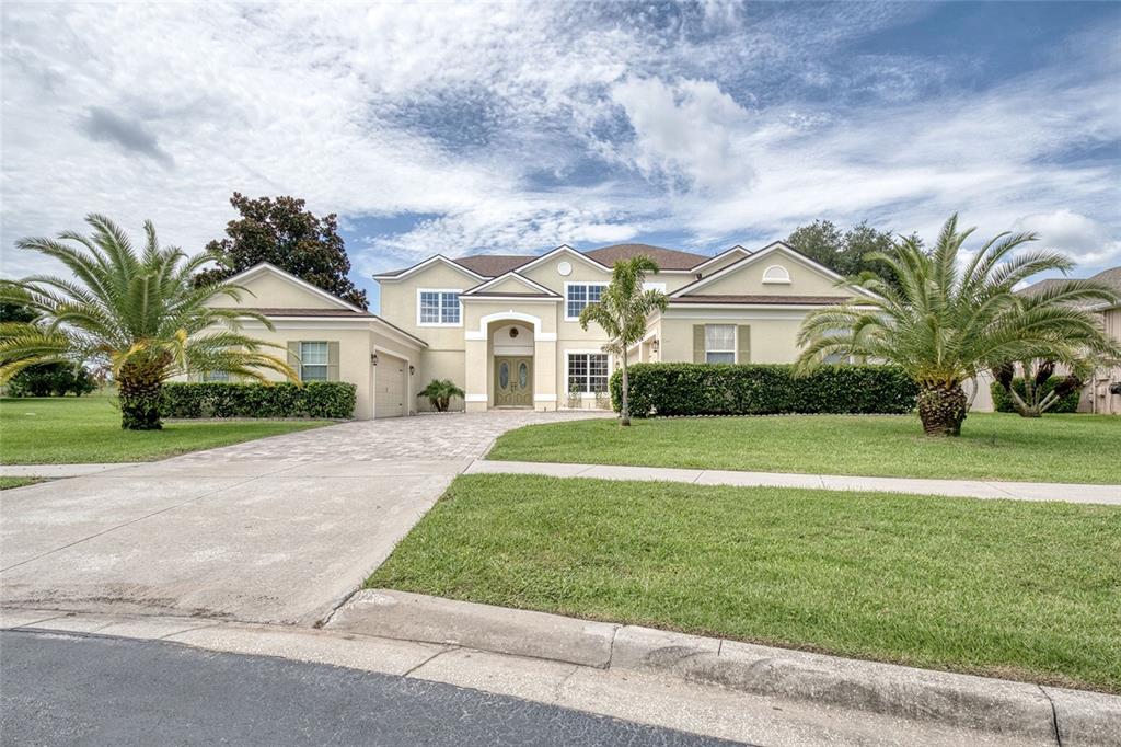 A two-story suburban house with a paved driveway, palm trees, and a manicured lawn — 2924 MAJESTIC ISLE DRIVE, CLERMONT, FL