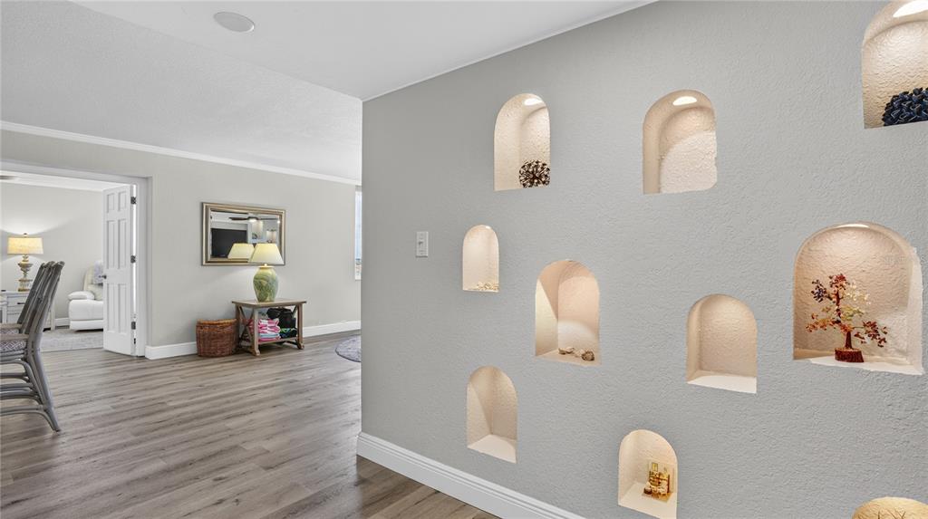 A gray wall features multiple arched, recessed niches with interior lighting, overlooking a living area — 1480 GULF BOULEVARD UNIT 601, CLEARWATER BEACH, FL