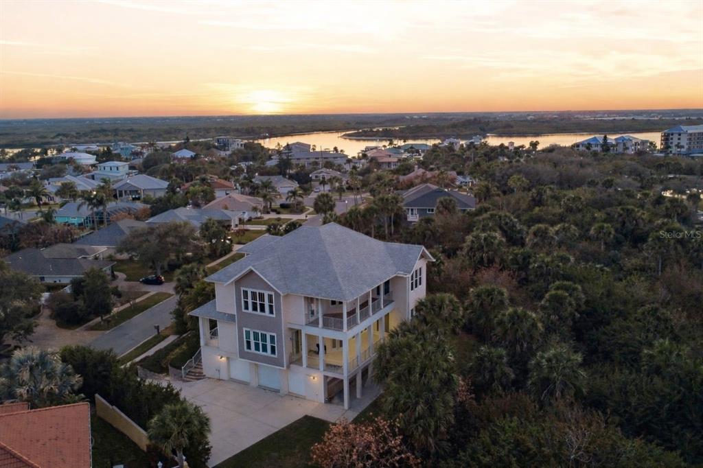 An aerial view shows a multi-story house with a garage and balconies near a waterway — 2142 VILLA WAY, NEW SMYRNA BEACH, FL