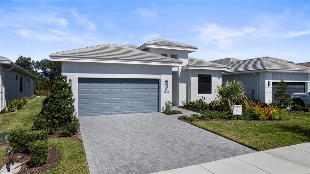 A modern single-story house with a gray garage door and a paved driveway — 4984 FAIRHOPE CIRCLE, LAKEWOOD RANCH, FL