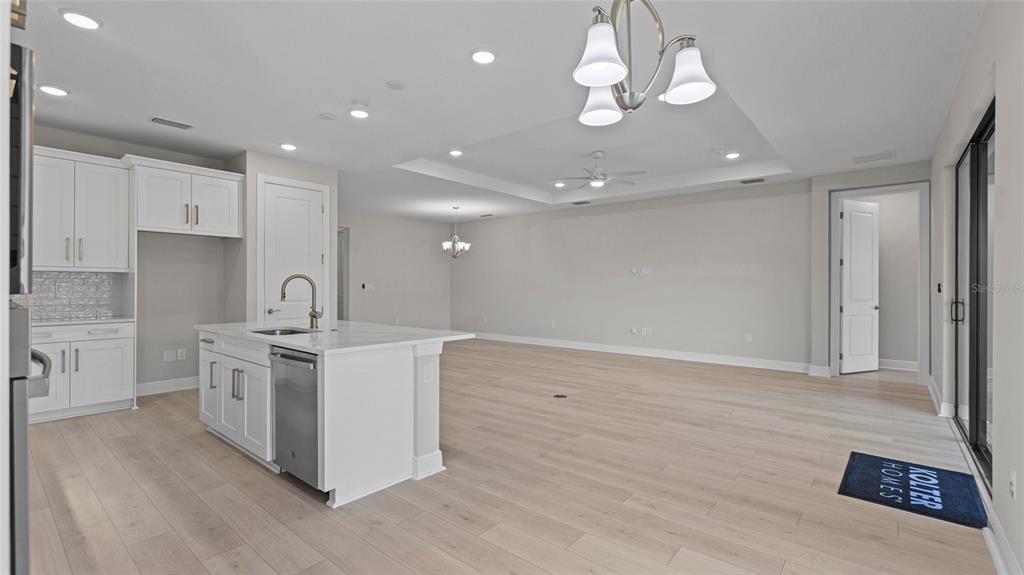 A bright, open-concept kitchen and living area features white cabinetry, a center island, and flooring — 4984 FAIRHOPE CIRCLE, LAKEWOOD RANCH, FL