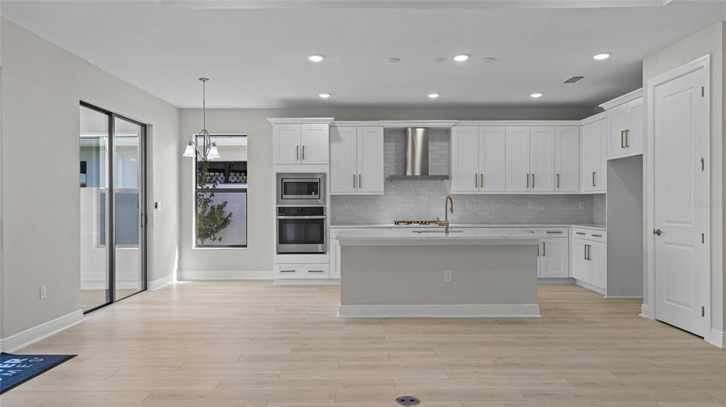 A modern kitchen features white cabinetry, a center island, stainless steel appliances, and light flooring — 4984 FAIRHOPE CIRCLE, LAKEWOOD RANCH, FL