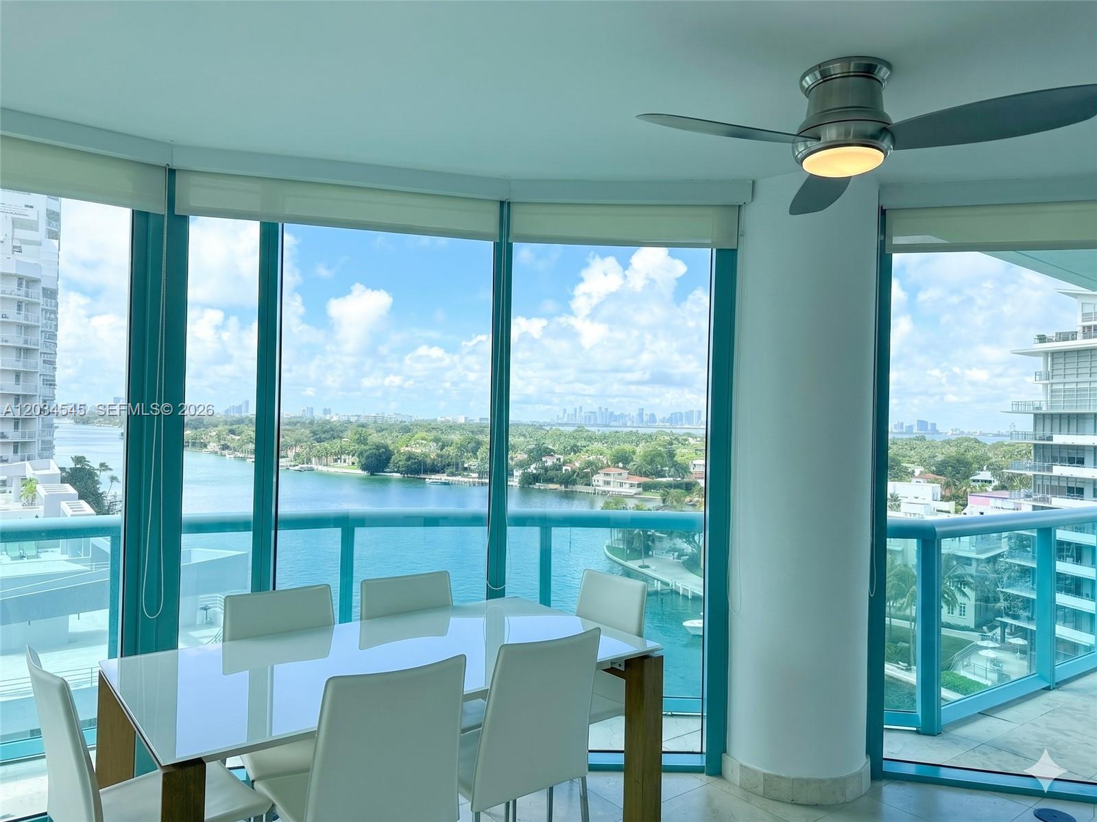 A dining area with a white table and chairs overlooks a bay and city skyline — 6000 Indian Creek Dr # 10A, Miami Beach FL 33140, MIAMI BEACH, FL