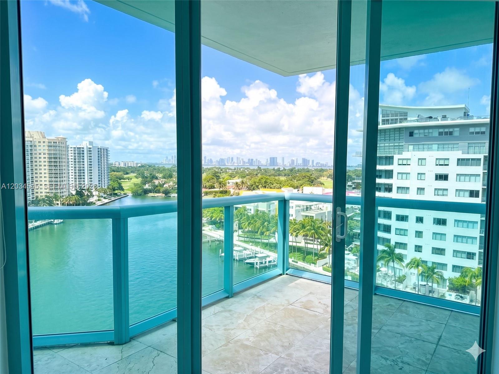 A view from a balcony looking out over a waterway, palm trees, and city skyline — 6000 Indian Creek Dr # 10A, Miami Beach FL 33140, MIAMI BEACH, FL