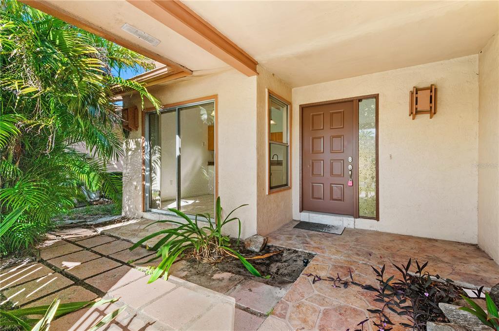 The exterior entryway features a brown door, stone flooring, and a sliding glass door — 6479 ROYAL WOODS DRIVE, FORT MYERS, FL