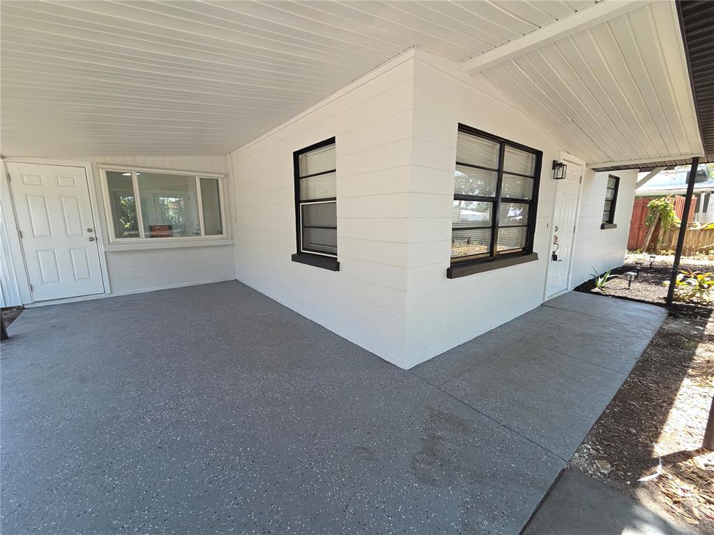 A white house exterior features a gray speckled concrete patio and black-framed windows — 419 32ND AVENUE E, BRADENTON, FL