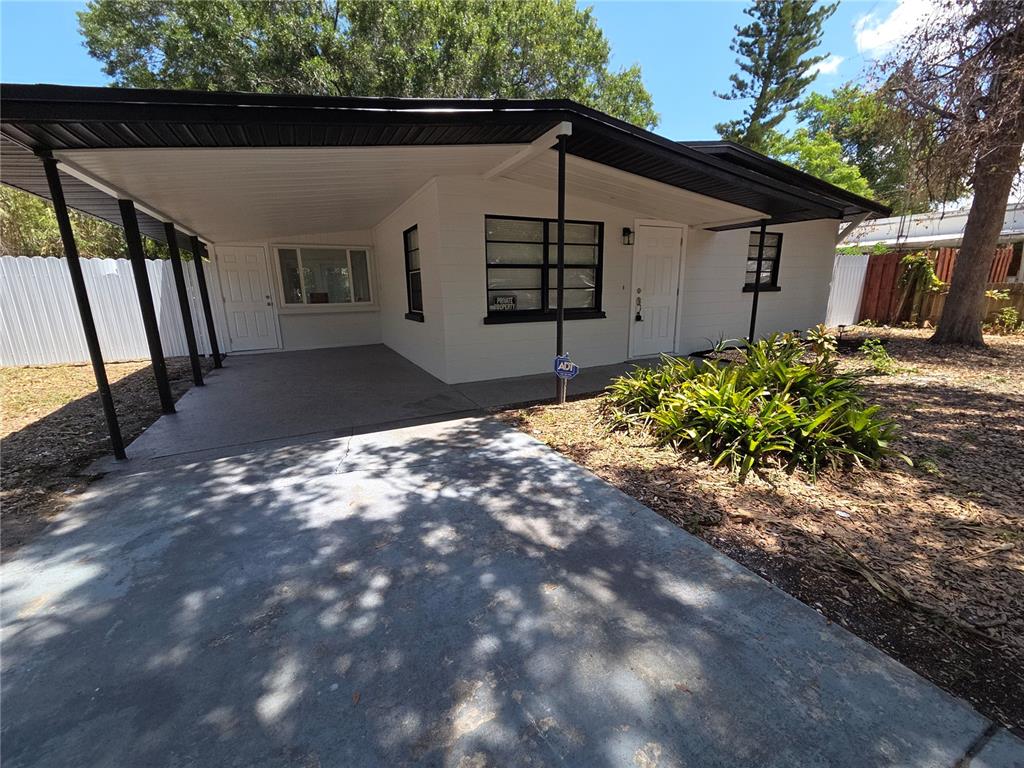 A white single-story house with a black roof, carport, and a concrete driveway — 419 32ND AVENUE E, BRADENTON, FL