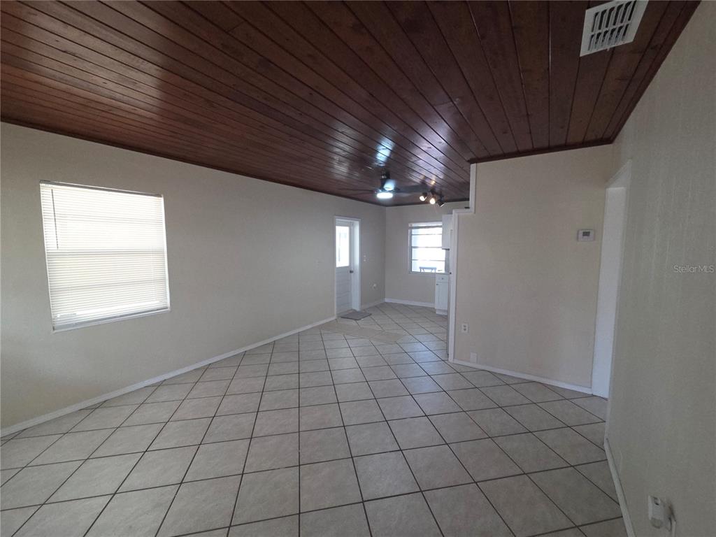 An open living area features light-colored floor tiles and a dark wood-paneled ceiling — 419 32ND AVENUE E, BRADENTON, FL