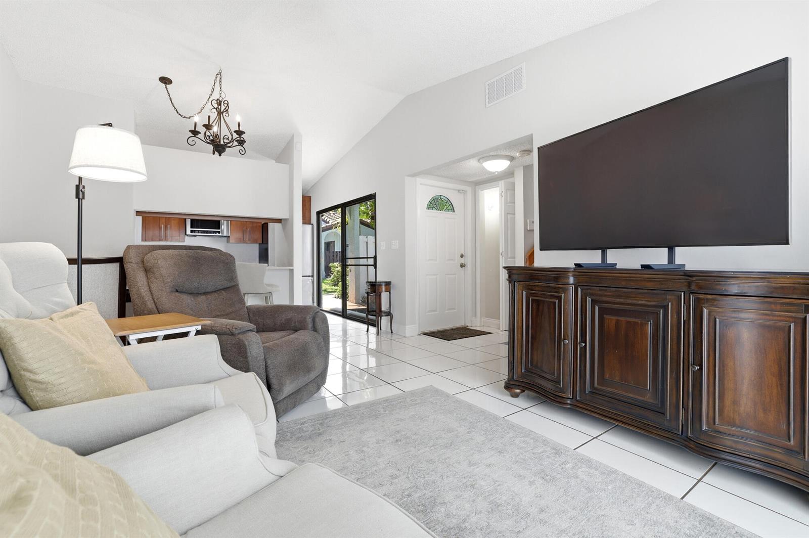 A living room with white tile floors, a large television on a wooden console, and furniture — 22316 Pineapple Walk Drive, Boca Raton FL 33433, BOCA RATON, FL