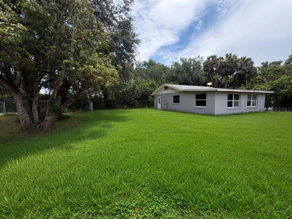 A gray single-story house sits on a large, grassy lot with mature trees — 3312 W 5TH STREET, SANFORD, FL