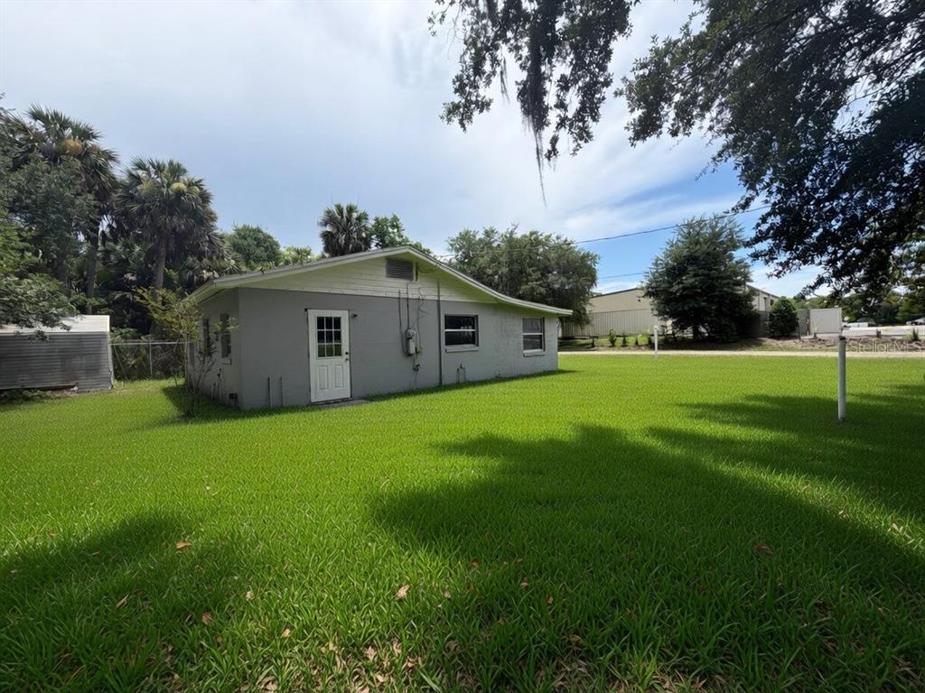 A gray, single-story house with a white door sits on a large, grassy lawn — 3312 W 5TH STREET, SANFORD, FL
