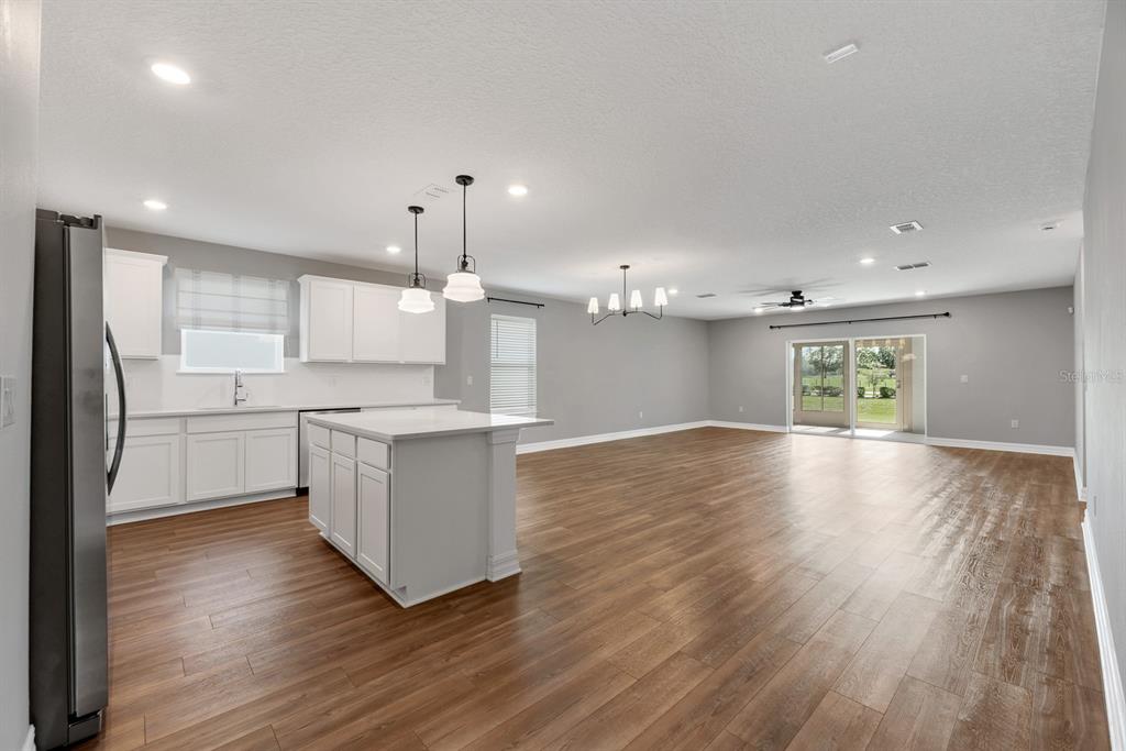 A kitchen with white cabinets and a center island opens into a large living area — 9514 SUMMERS CAY CIRCLE, THONOTOSASSA, FL