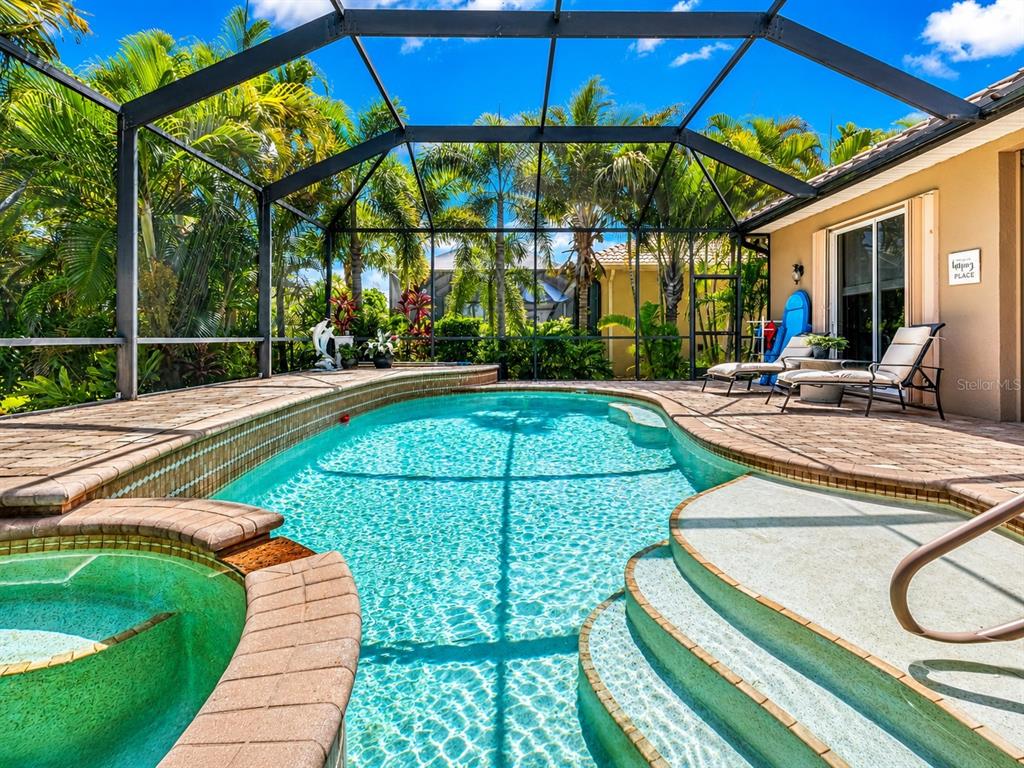 A screened-in swimming pool and hot tub on a paved patio with lounge chairs — 24228 PEPPERCORN ROAD, PUNTA GORDA, FL