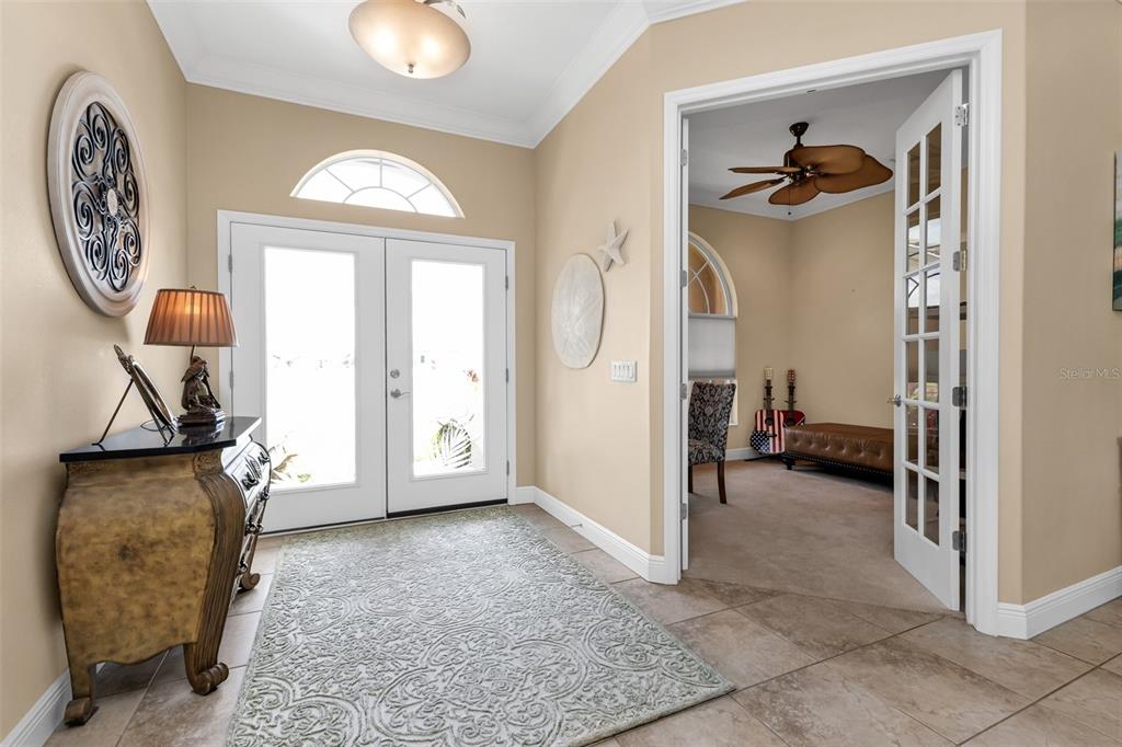 A foyer with tile flooring, a patterned rug, and double doors leading to a room — 24228 PEPPERCORN ROAD, PUNTA GORDA, FL