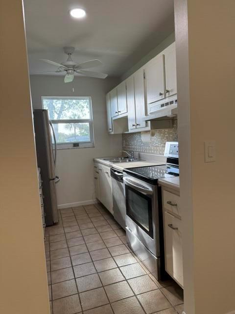 A galley kitchen features white cabinets, stainless steel appliances, and light-colored tile flooring — 7293 W Oakridge Circle, Lake Worth FL 33462, LAKE WORTH, FL