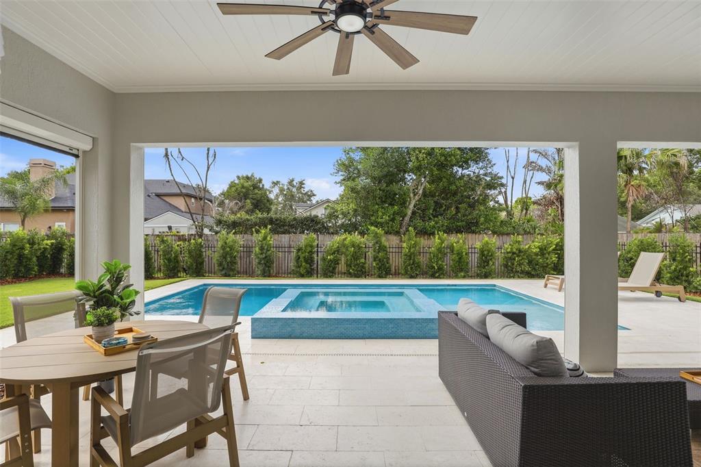 A backyard features a swimming pool with a raised spa and a covered patio area — 1750 CAROLLEE LANE, WINTER PARK, FL