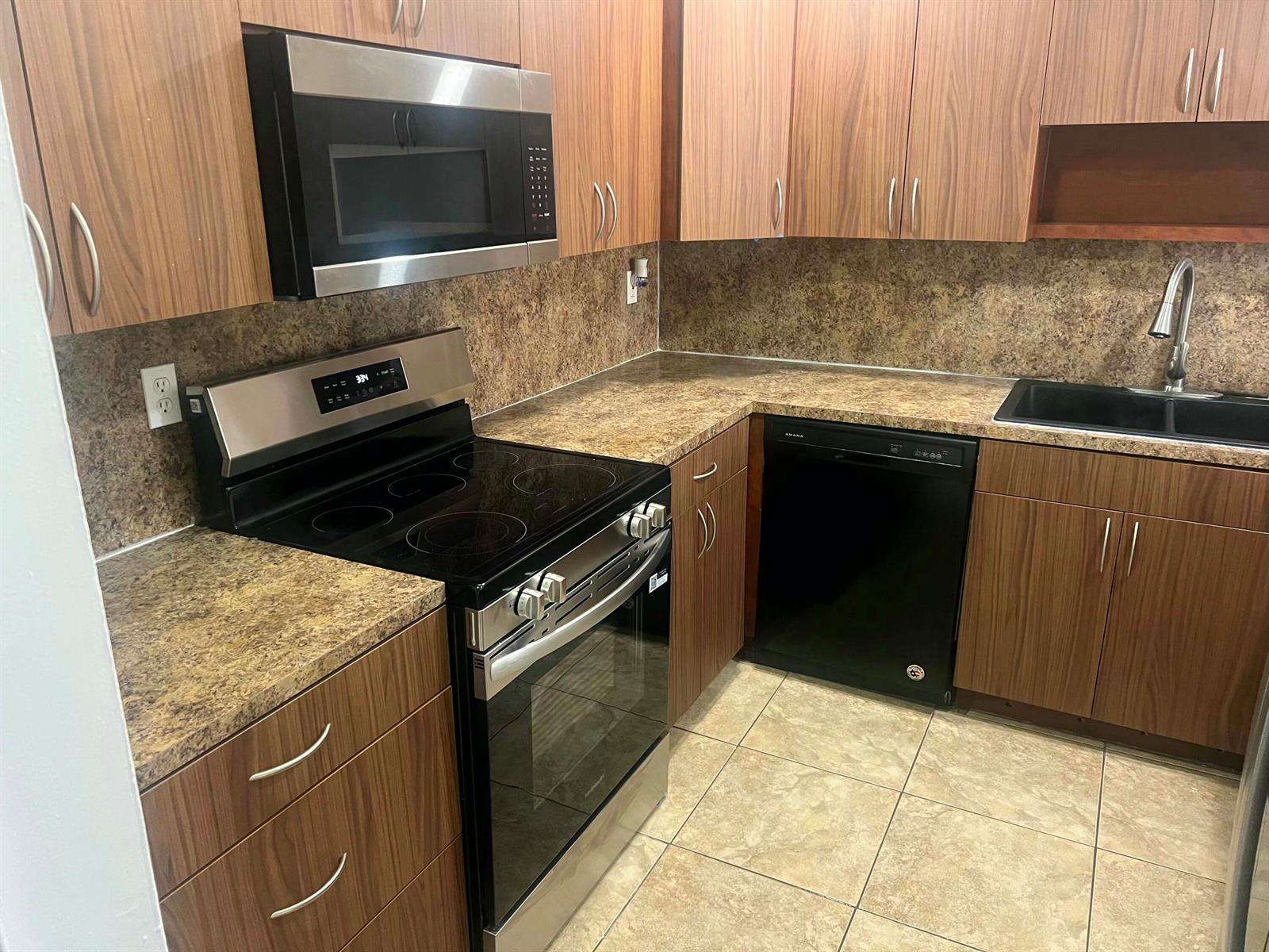 A kitchen features wood-grain cabinets, stainless steel appliances, a black dishwasher, and brown laminate countertops — 7000 NW 186th Street # 316, Hialeah FL 33015, HIALEAH, FL