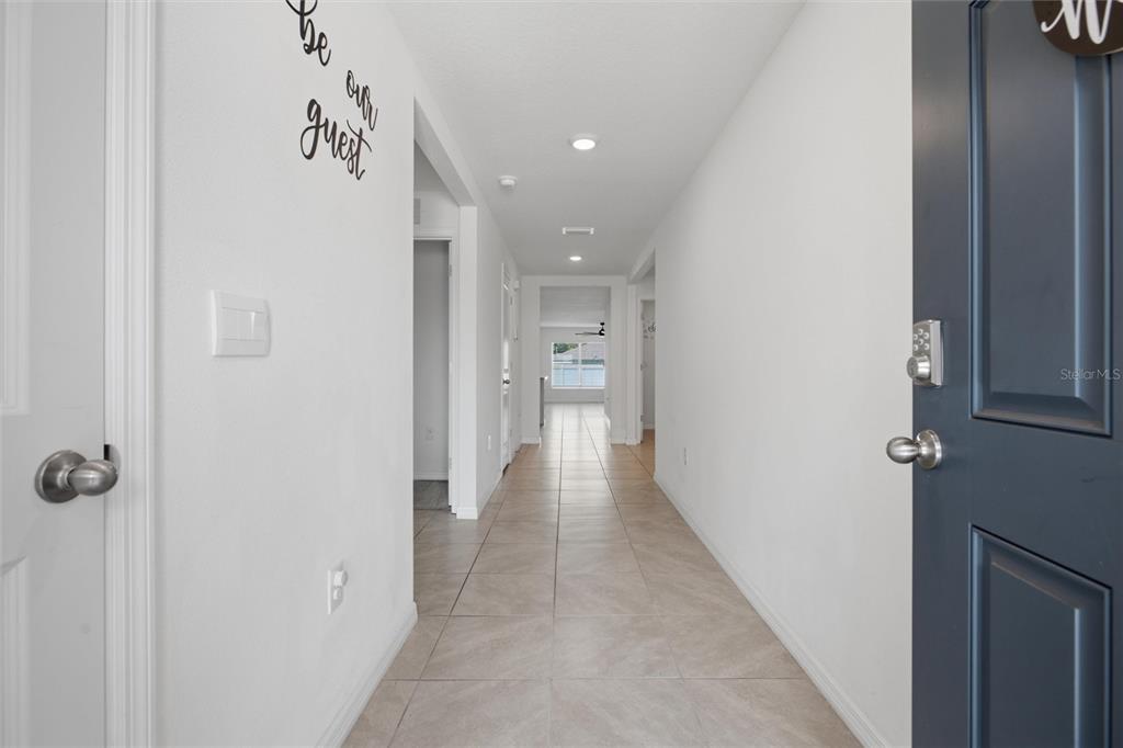 A view from an entryway looking down a tiled hallway toward a living area — 9295 VAN ALLEN WAY, SPRING HILL, FL