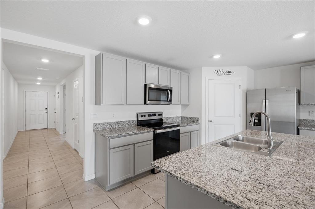A kitchen features gray cabinets, granite countertops, stainless steel appliances, and tile flooring — 9295 VAN ALLEN WAY, SPRING HILL, FL