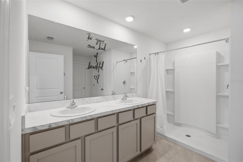 A bathroom features a double vanity with marble-look countertops, grey cabinets, and a walk-in shower — 9295 VAN ALLEN WAY, SPRING HILL, FL