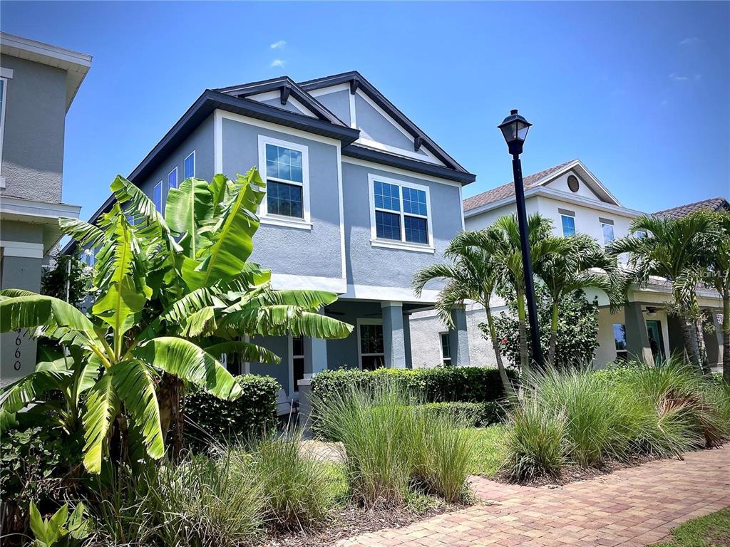 A two-story blue house with a covered porch, palm trees, and a brick walkway — 14654 WATOWAN ALLEY, WINTER GARDEN, FL