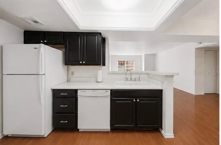 An empty living room with light wood flooring and a pass-through to the kitchen — 10200 GANDY BOULEVARD N UNIT 714, ST PETERSBURG, FL