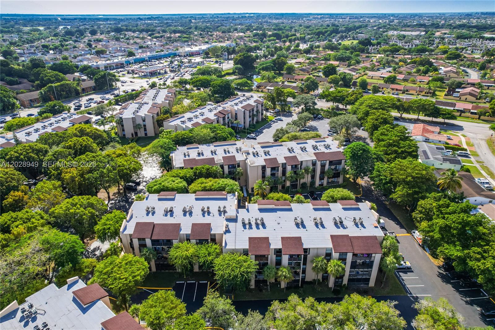 An aerial view shows several multi-story apartment buildings surrounded by trees and parking lots — 14501 N Kendall Dr # 212H, Miami FL 33186, MIAMI, FL
