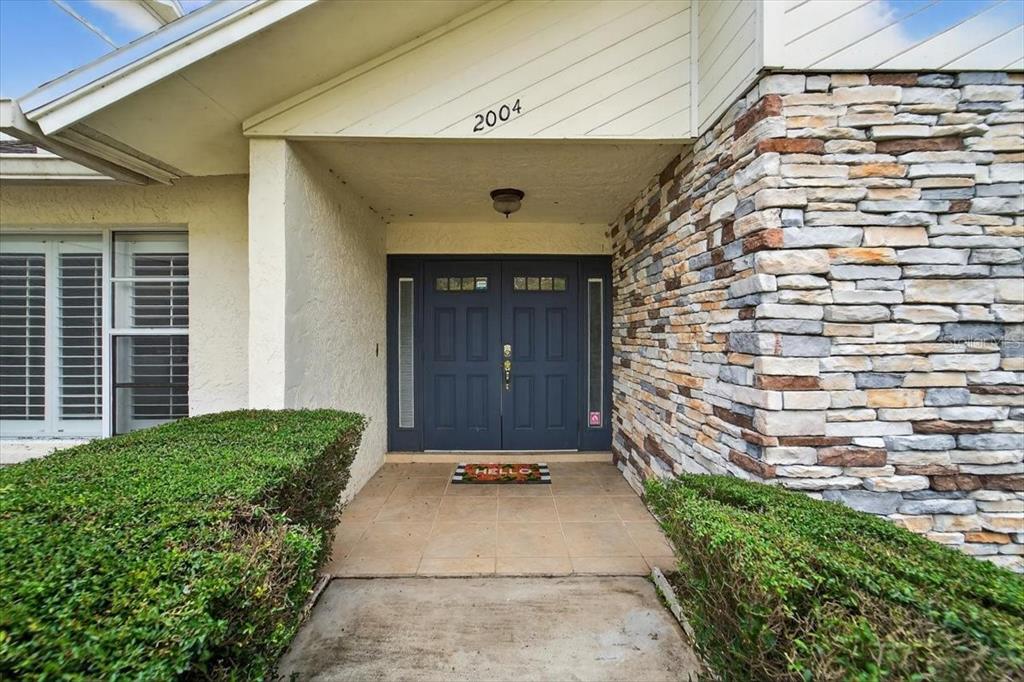 The exterior entrance features a double door, stone veneer siding, and a tiled porch area — 2004 N GOLFVIEW DRIVE, PLANT CITY, FL