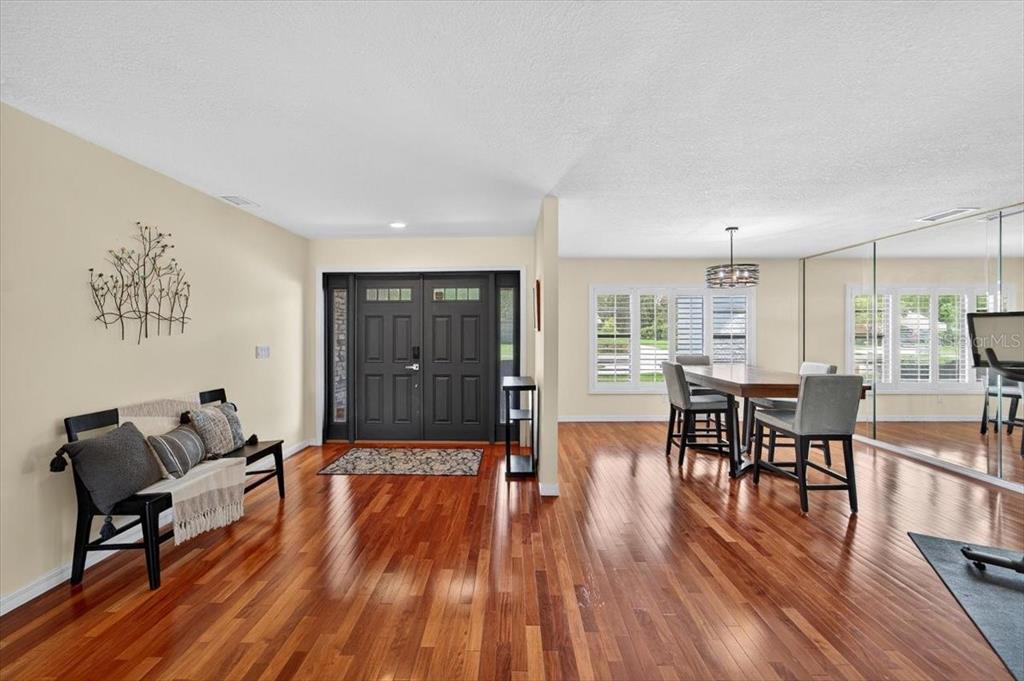 An entryway with hardwood floors leads to a dining area featuring a mirrored wall — 2004 N GOLFVIEW DRIVE, PLANT CITY, FL