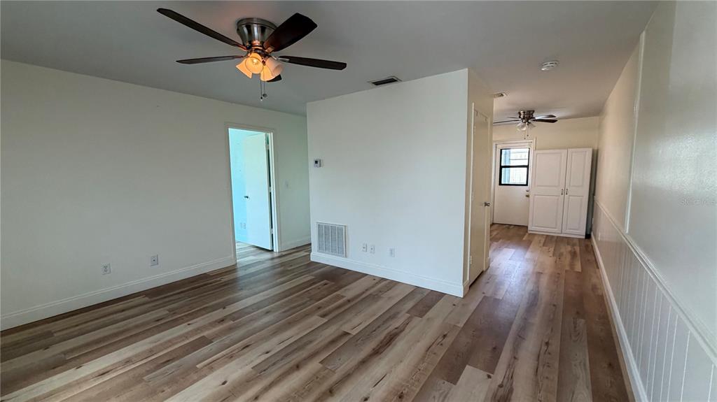 A living area with wood-look flooring, a ceiling fan, and an adjacent kitchen space — 10147 TRAMORE AVENUE UNIT #A, ENGLEWOOD, FL