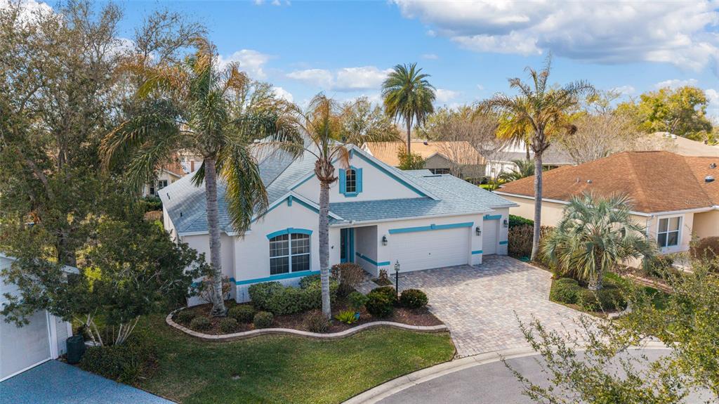 An aerial view of a single-story house with a paved driveway and palm trees — 646 STRATFORD LANE, THE VILLAGES, FL