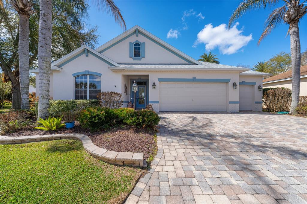 A single-story house with a paved driveway, blue trim, and palm trees in the front yard — 646 STRATFORD LANE, THE VILLAGES, FL