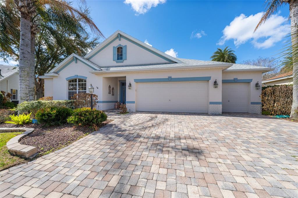 A single-story house with a paved driveway, a three-car garage, and blue trim accents — 646 STRATFORD LANE, THE VILLAGES, FL