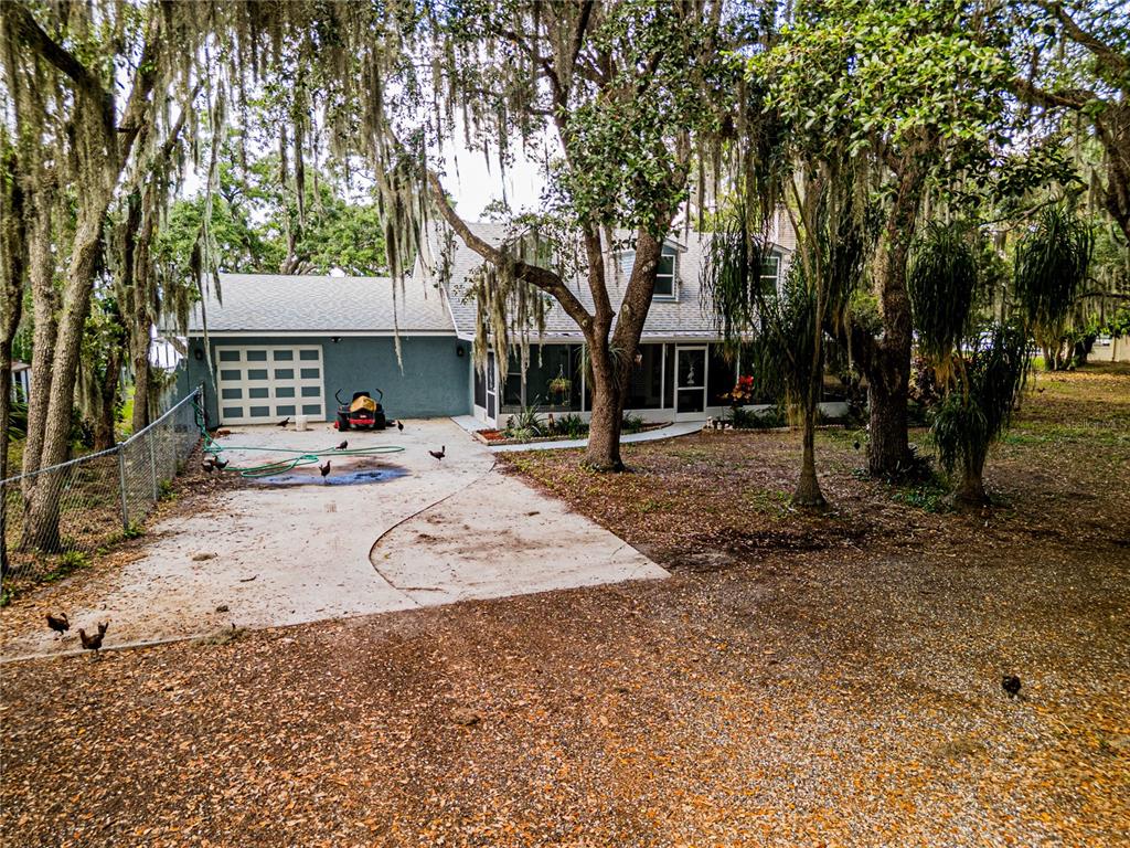 A two-story house with a garage, screened porch, and chickens in the yard — 1502 LAKE JOSEPHINE DRIVE, SEBRING, FL