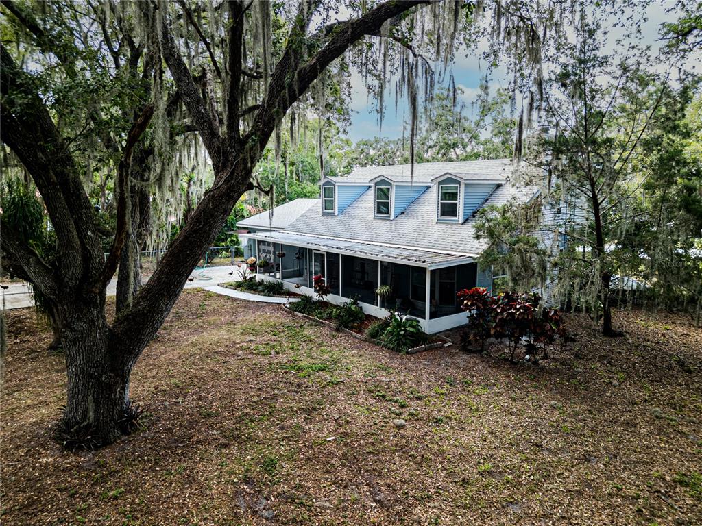 An elevated view of a blue house with a screened porch and three roof dormers — 1502 LAKE JOSEPHINE DRIVE, SEBRING, FL