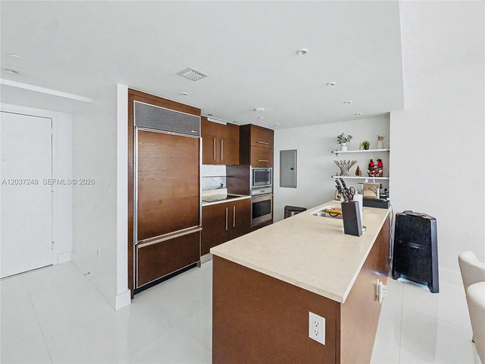 A modern kitchen features dark wood cabinetry, a large island, and stainless steel appliances — 465 Brickell Ave # 1605, Miami FL 33131, MIAMI, FL