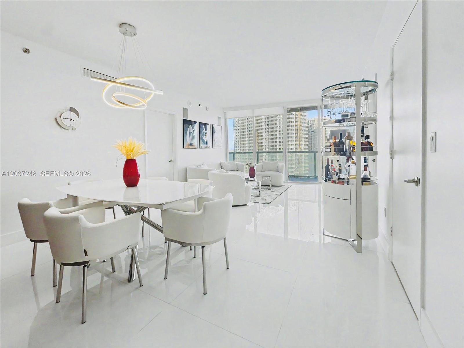 A bright, all-white dining and living area features modern furniture, a glass bar, and floor-to-ceiling windows — 465 Brickell Ave # 1605, Miami FL 33131, MIAMI, FL