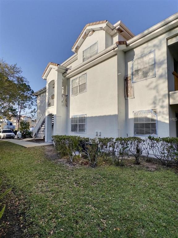A multi-story apartment building exterior features white stucco walls and windows covered with plastic sheeting — 13803 FAIRWAY ISLAND DRIVE UNIT 1618, ORLANDO, FL